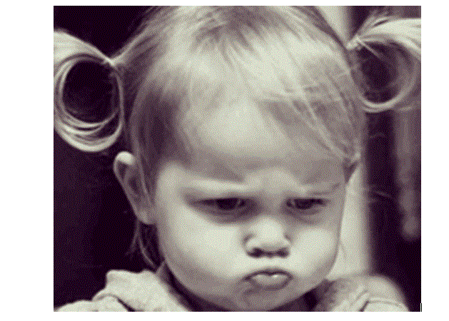 A young child with pigtails and a pouty expression looks directly at the camera, embodying a sulky demeanor in a black-and-white photograph.